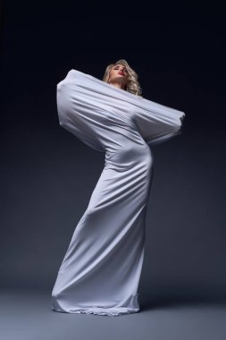 Konfor bölgesinin konforu, beyaz örtüye sarılmış uzun kıvırcık saçlı, çekici, çıplak kadın modelin tüm vücudu.