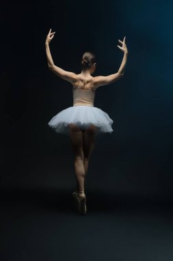 A ballet dancer performs gracefully in a white tutu, emphasizing movement and artistry against a dark backdrop. clipart