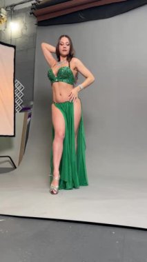 Yetenekli bir dansçı göbek dansı becerilerini sergilerken göz kamaştırıcı yeşil bir kostüm içinde zarafet saçar..