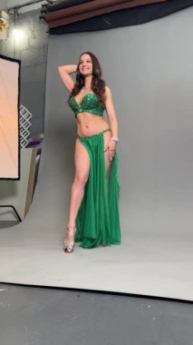 Zarif bir kadın büyüleyici bir göbek dansı yapar. Parlak yeşil bir elbise giyer, güzelliğini ve yeteneğini gösterir..