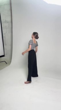 Stüdyo ortamında zarif bale figürleri sergileyen bir kız yaratıcı bir prova yapıyor..