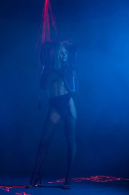 Bir model, mavi sis ve lazer ışıklarının arasında şık pozlar verir..