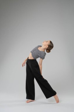 Genç bir kız atletizm ve sanatsal ifadesini vurgulayarak bir stüdyoda modern dans gösterisi yapıyor..