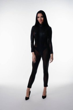 Bir güzellik, siyah iç çamaşırlarıyla zarafetini sergiliyor. İyi ışıklandırılmış bir stüdyo ortamında zarafetle poz veriyor..