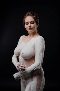 Bir model, karanlık bir stüdyo ortamında eşsiz vücut boyama tekniklerini sergilerken kendine güvenerek poz verir..