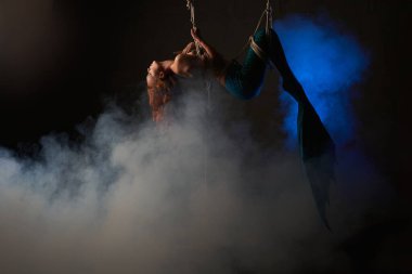 İplere takıldıktan sonra havada sarkan mavi kuyruklu kızıl saçlı genç bir deniz kızı.