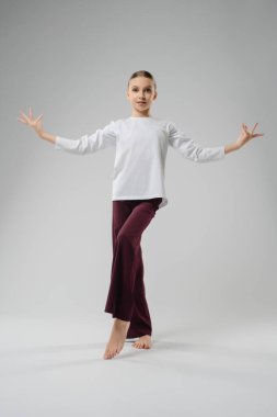 Genç bir kız dans stüdyosunda zarif bir poz veriyor, sanatını ve yeteneklerini sergiliyor..