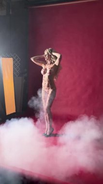 Kadın, canlı kırmızı bir arka planda çıplak modellik yaparken sanatsal vücut sanatını sergiliyor..