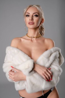 Kendine güvenen bir kadın, şık bir kürk manto ile tamamlanmış şık bir iç çamaşırı giyerek tarzını ve zarafetini sergiliyor..