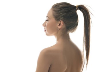 Uzun düz saçlı, at kuyruklu bir kadın sakin duruyor, profili parlak bir arka planda aydınlanıyor, sakinlik saçıyor..