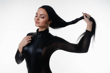 Çekici bir kadın, minimalist bir stüdyo ortamında kendine güvenen ve zarafet gösteren iç çamaşırlarıyla poz verir..