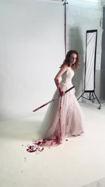 Bir düğün gecesinde sahne arkasında, çarpıcı bir elbise giymiş bir kadın dramatik bir etki yaratmak için sanatsal bir poz verir..