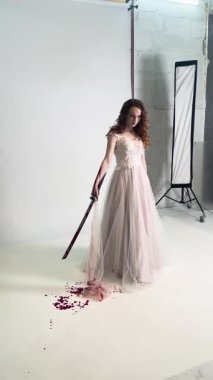 Bir düğün çekiminin kulisinde, zarif bir elbise giymiş bir kadın çiçek aksanı ve yaratıcı aksesuarlarla süslenir..