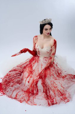 Göz alıcı, kanlı bir elbiseyle süslenmiş bir gelin, zarif bir şekilde oturur, elinde bıçakla, karanlık ve rahatsız edici bir güzelliği somutlaştırır..