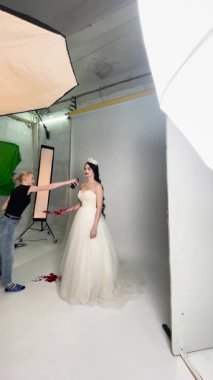 Çarpıcı beyaz elbiseli bir gelin sahne arkasında benzersiz bir sanatsal düzenle poz veriyor, güzellik ve yaratıcılık sergiliyor..