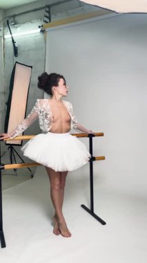 Bir stüdyo ortamında, bir kadın etek giyip dans ederken üstsüz poz verir..