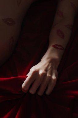 Bir kadın, zengin kırmızı kadife bir ortamda, şehvetli bir pozla süslenir ve mahremiyeti yakalar..