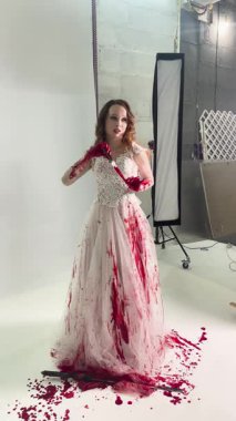 Bir gelin, göz kamaştırıcı bir elbise, canlı kırmızı boya serpiştirilmiş, sanatsal yetenekler ve yaratıcılık sergiliyor..