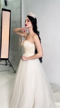 Bir gelin çarpıcı bir gelinlik içinde fotoşopa hazırlanıyor, canlı bir ortamda güzelliği ve zarafeti sergiliyor..