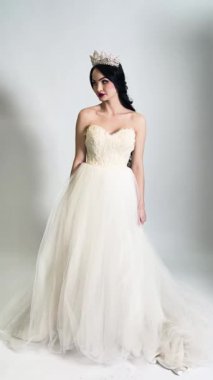 Göz kamaştırıcı gelinlikli güzel bir kadın özel gününe hazırlanıyor, sahne arkasında zarafet ve zarafet sergiliyor..