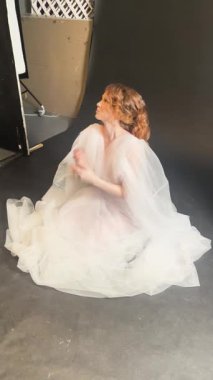 Bir gelin zarif elbisesiyle hazırlanır ve poz verir, düğün töreninden önce neşe saçar..