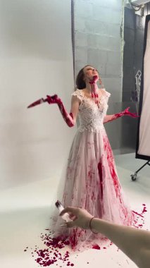 Özenle hazırlanmış gelinlikli bir kadın sahne arkasında dramatik unsurlarla sanatsal bir gösteri sergiliyor..