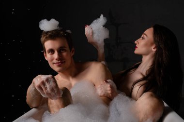 Erkek ve kadın yatakta rahatlar, birbirlerine eşlik ederken ve yakınlaşırken selfie çekerler..