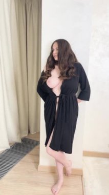 Siyah bornoz giymiş bir kadın otel odasında fotoğraf çekimine hazırlanıyor..