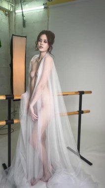 Model, bir stüdyoda zarif bir şekilde poz veriyor. Kendine olan güvenini ve güzelliğini akıcı kumaşla sergiliyor..