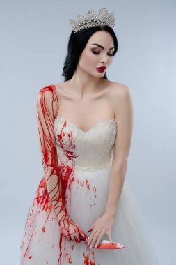 Beyaz iç çamaşırı giymiş çarpıcı bir gelin kolunda kan ve elinde bıçakla dramatik bir kontrastı gösterir..