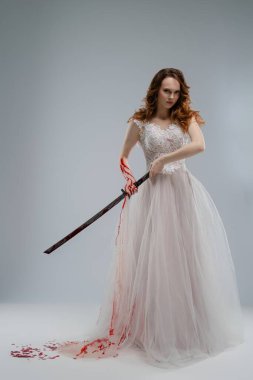 Gelin gibi giyinmiş bir kadın katana tutuyor, elbisesi kanla boyanmış, dramatik ve yoğun bir atmosferi çağrıştırıyor..