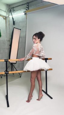 Kendine güvenen bir kadın, sanatsal bir stüdyoda dinamik bir şekilde poz veren etek ve dantel elbisesiyle vücudunu sergiliyor..