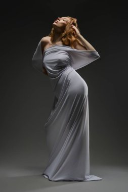 Bir kadın iç çamaşırlarıyla güzellik ve zarafet sergilerken, etrafında yumuşak kumaşlarla baştan çıkarıcı bir poz veriyor..