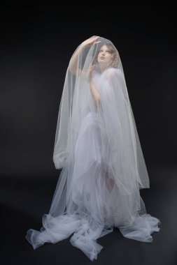 Çekici bir kadın zarif bir şekilde dantelli bir gelinlikle poz verir, çok güzel ve büyüleyici..