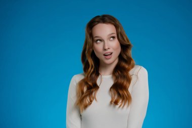 Yumuşak ışıkla dolu bir stüdyoda, bir kadın duygularını neşeli bir ifadeyle gösterir. Uzun saçları zarifçe dökülüyor, çekimin dinamik atmosferine ekleniyor..