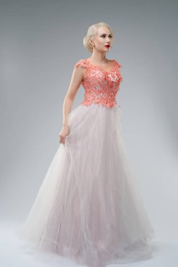 Göz alıcı bir gelinlik içinde, üzerinde kan lekeleri olan zarif bir kadın. Tarafsız bir stüdyoda geçiyor, özgüven ve benzersizlik sergiliyor, geleneksel gelinlik estetiğini cesur bir şekilde birleştiriyor.