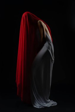 Bir kadın çarpıcı bir seçimde canlı kumaşlarla zarif bir hareket sergiliyor, modellik becerilerini vurguluyor..