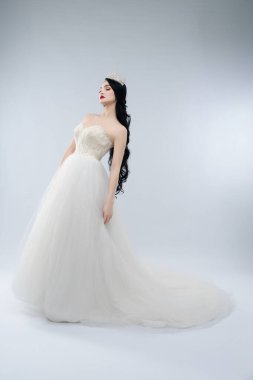 Güzel bir kadın zarif bir şekilde beyaz bir gelinlikle poz verir, zarafet ve cazibe saçar..