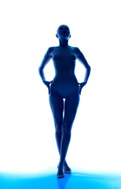 Ayakta duran bir figürün koyu bir silueti, elleri kalçasında, parlayan mavi bir ışıkla çevrili olarak poz verir..