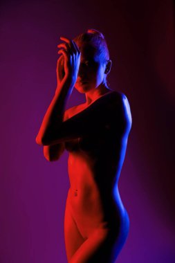 Bir kişi canlı mor ve kırmızı ışığa karşı zarif bir şekilde siluette duruyor ve çarpıcı bir görsel karşıtlık oluşturuyor..