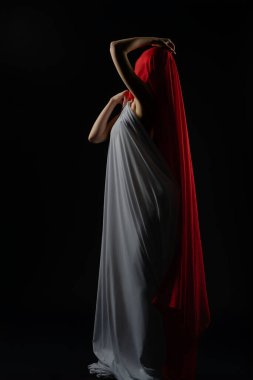 Bir model zarif bir poz sergiliyor dalgalı beyaz bir elbise ve canlı kırmızı bir duvak giyiyor..