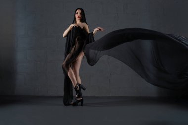 Kendine güvenen bir kadın zarif iç çamaşırlarını modern bir iç mekan ortamında sergiliyor..