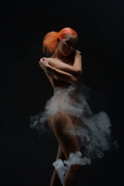 Kızıl saçlı bir kadın zarif bir şekilde çıplak poz veriyor, kısmen kumaş ve yumuşak dumanla kaplı, çok güzel ve cezbedici..