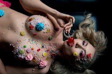 Bir kadın, elinde lolipopla kendinden emin bir şekilde şekerlemelerden esinlenerek vücut sanatını sergiliyor..