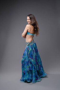 Büyüleyici mavi kostümlü bir kadın dans yeteneğini sergiliyor. Gösteri sırasında özgüven ve zarafetle hareket ediyor..