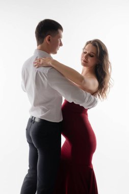 Basit ve zarif bir ortamda hamileliğin güzelliğini gösteren zarif bir şekilde dans eden bir çift birbirini kucaklıyor..