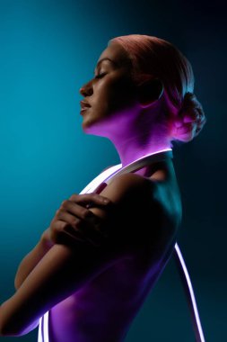 Zarif bir poz veren bir kadın, narin ışık ve canlı aksanlarla aydınlanan güzelliğini sergiler, sakin, sanatsal bir ortam yaratır..