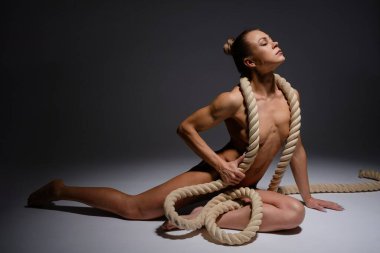 Güçlü bir kadın, ince bir stüdyoda iple zarifçe poz verir. Güç ve sanatla harmanlanır..