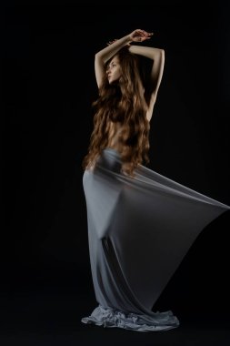 Bir kadın zarif bir şekilde poz verir, modellik yeteneklerini kapalı bir stüdyoda gösterir..