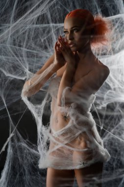 Çarpıcı kızıl saçlı bir kadın hassas bir ağ tuzağına takılıp büyüleyici ve ürkütücü bir atmosfer yaratıyor..